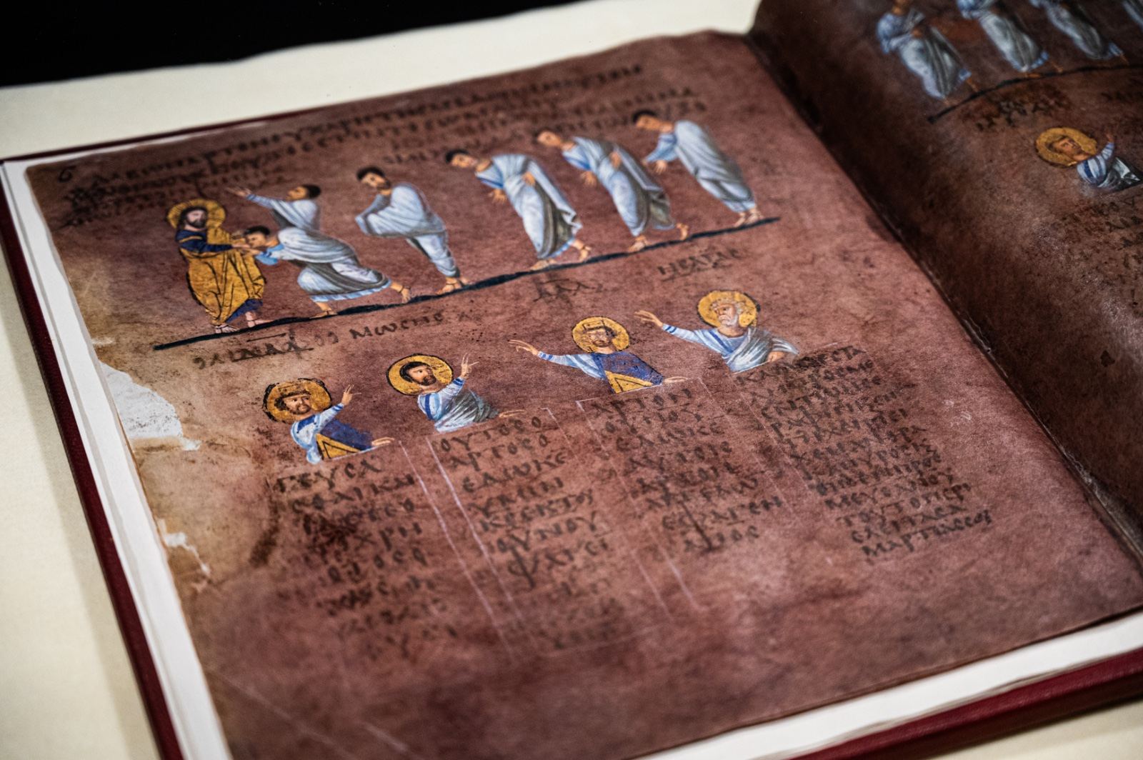 Il Codex di Rossano aperto su una pagina di porpora: in alto una fila di figure miniate, sotto i busti dei profeti e il testo greco