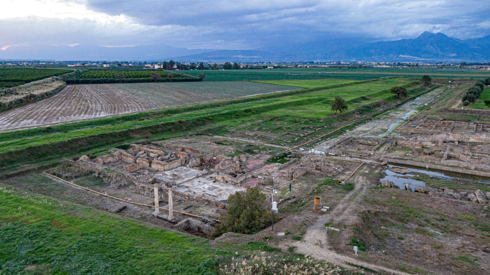 Gli scavi archeologici di Sibari visti dall'alto, tra i campi verdi della Piana, con le montagne sullo sfondo