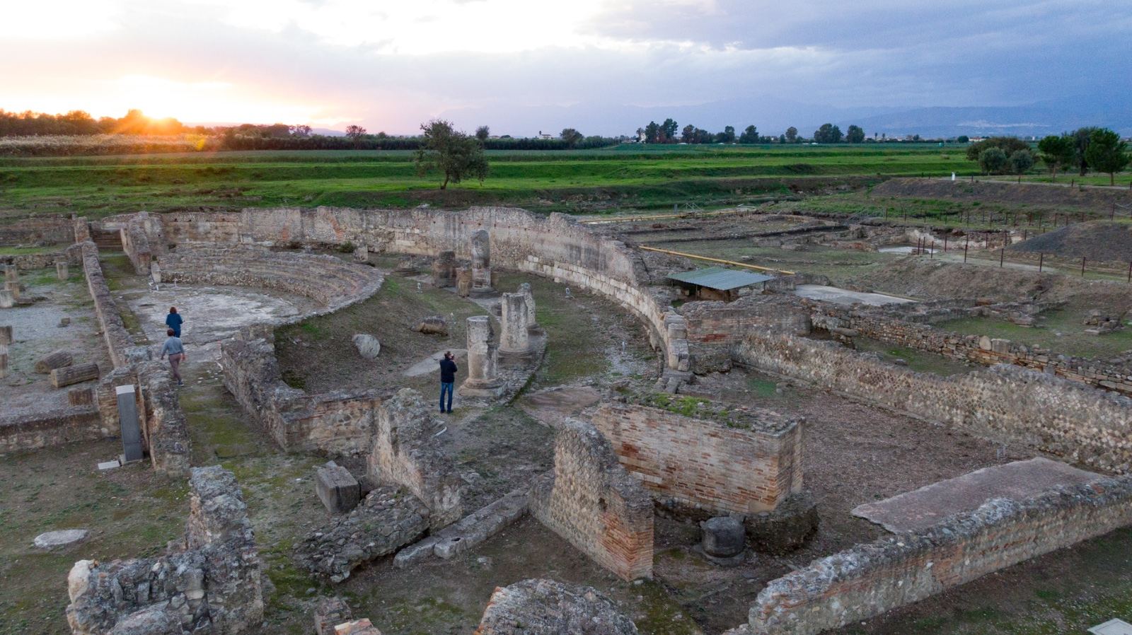 Le rovine di Sibari al tramonto, con due visitatori che camminano tra i muri antichi