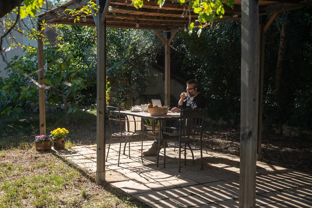 Un uomo prende il caffè al tavolo sotto la pergola