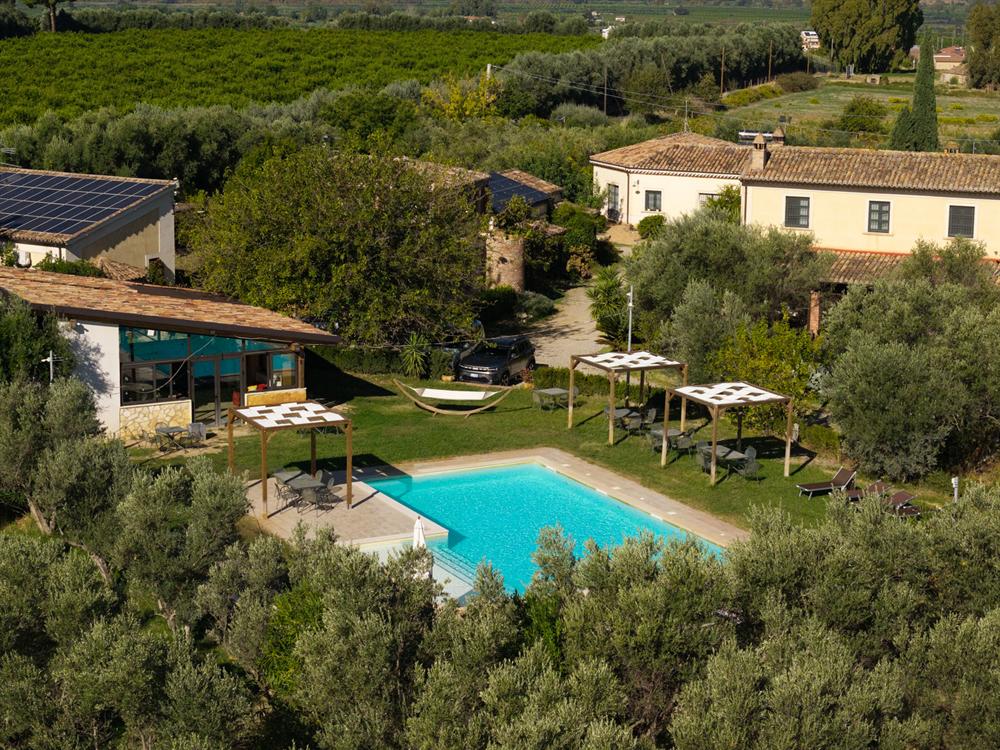 La piscina e gli edifici dell'agriturismo tra ulivi e agrumeti