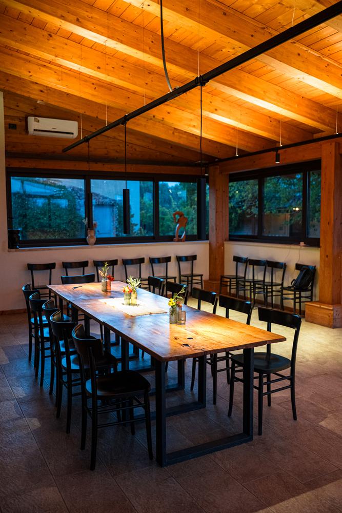 Il lungo tavolo in legno della sala, apparecchiato con fiori