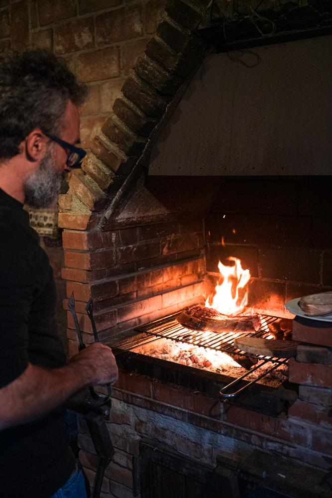 Un uomo cuoce la carne sulla brace del camino