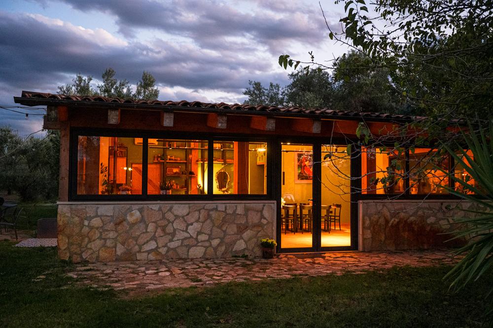La sala illuminata dall'interno, vista dal giardino al crepuscolo