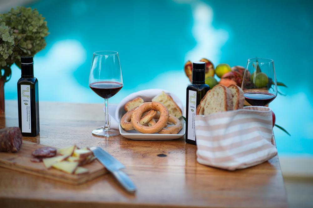 Due bottiglie di olio, taralli e calici di vino rosso sul tavolo