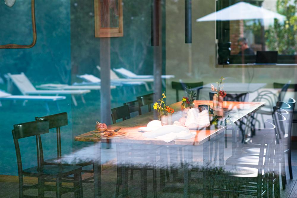 Il tavolo apparecchiato visto attraverso il vetro, con i lettini della piscina riflessi