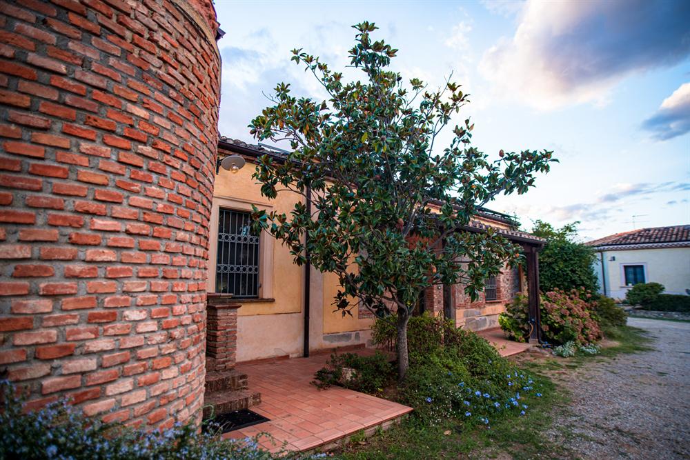 La torretta in mattoni e il portico, con un albero di magnolia