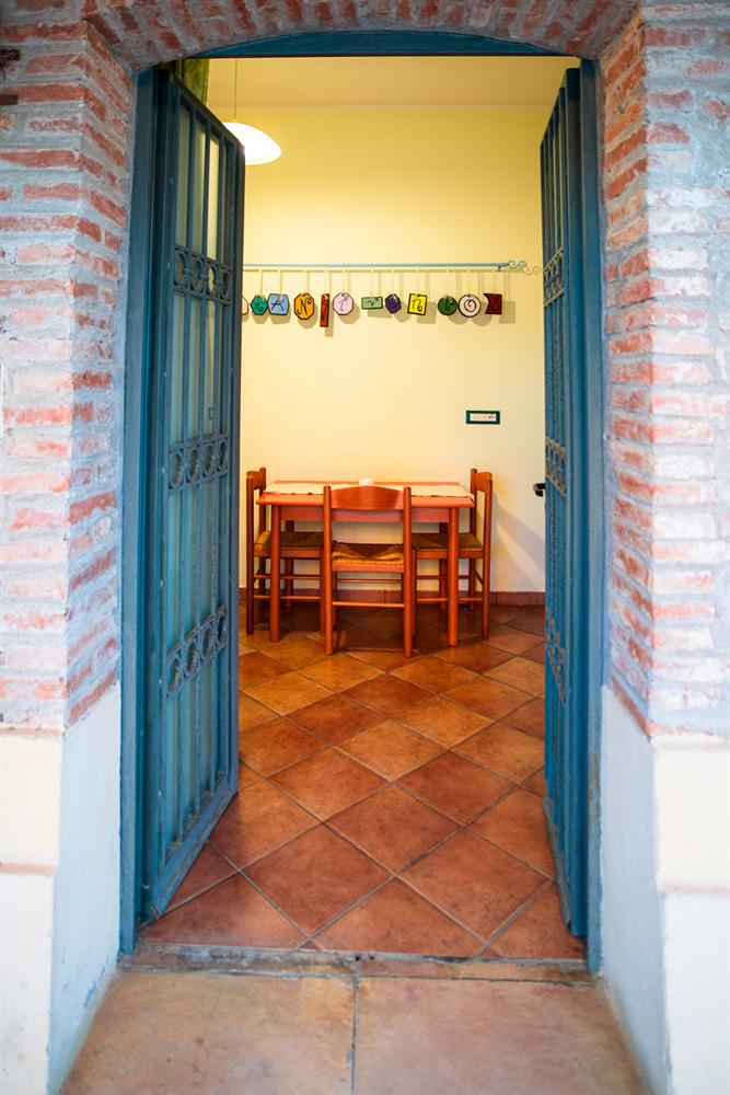 La porta aperta di un appartamento tra due pilastri di mattoni, con il tavolo all'interno