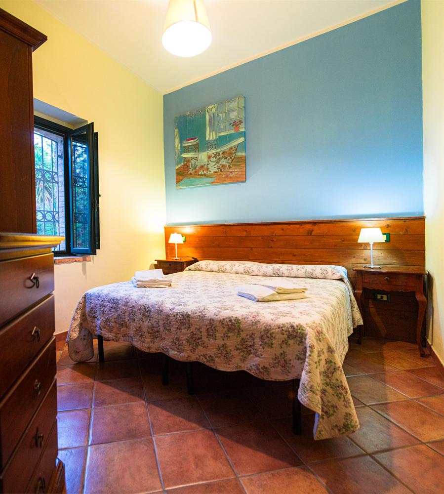 Camera matrimoniale azzurra con armadio e cassettiera in legno