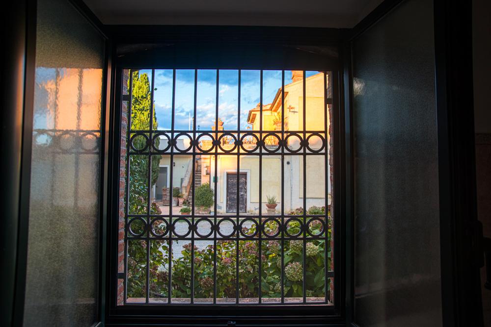 Una finestra con inferriata che si apre sul cortile al tramonto