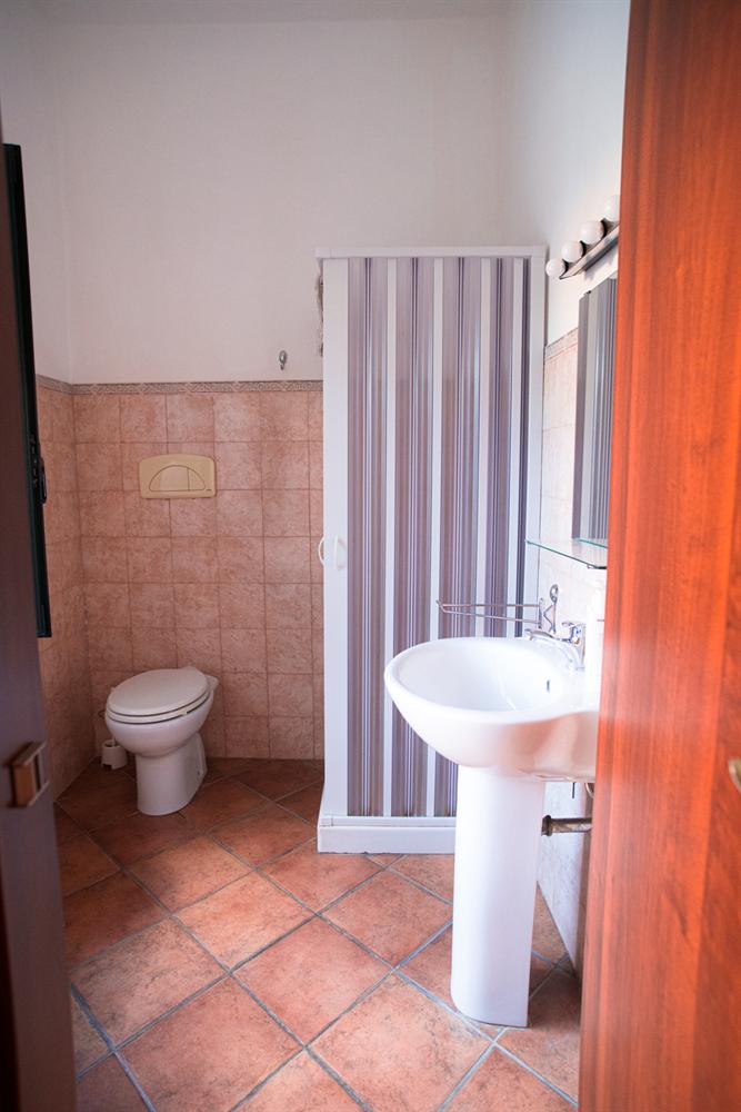 Bagno con doccia, lavabo a colonna e piastrelle color pesca