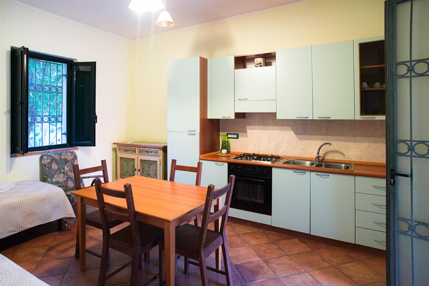 La cucina-soggiorno con angolo cottura, forno, tavolo e sedie