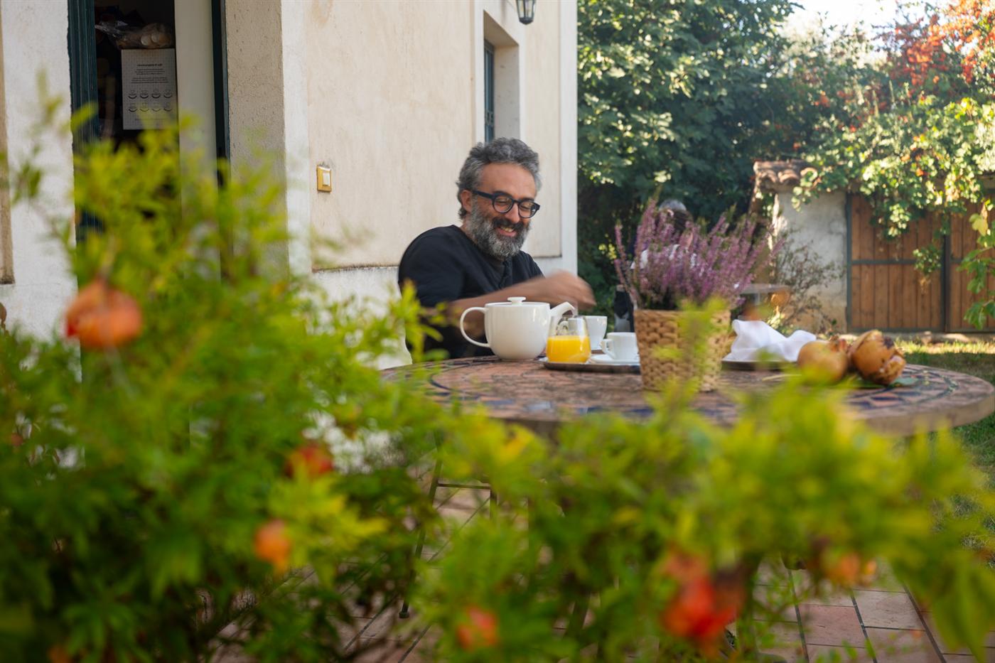 Colazione in giardino tra i melograni: un sorriso, il tè e il succo d'arancia sul tavolo